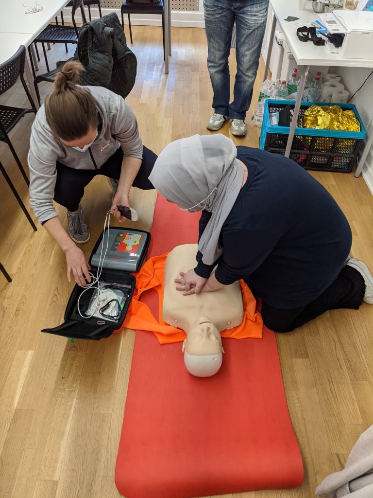 lady performing cpr on dummy while another lady watches